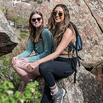 Two girls hiking and sitting on a rock
