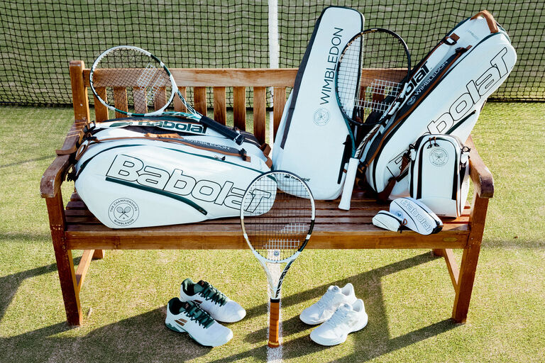Bench on a tennis court with racquets, bags, shoes and more on it