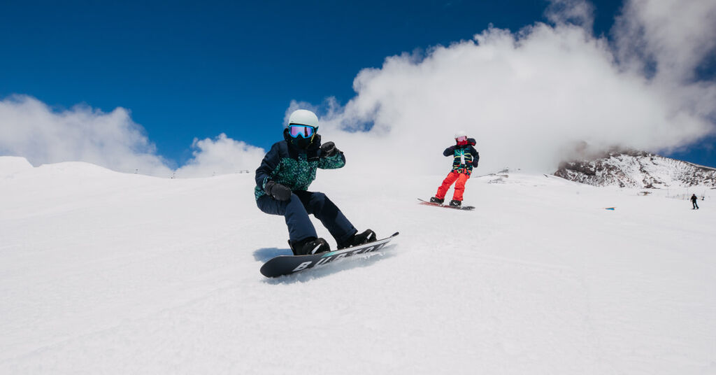 Two snowboarders riding on a sunny day