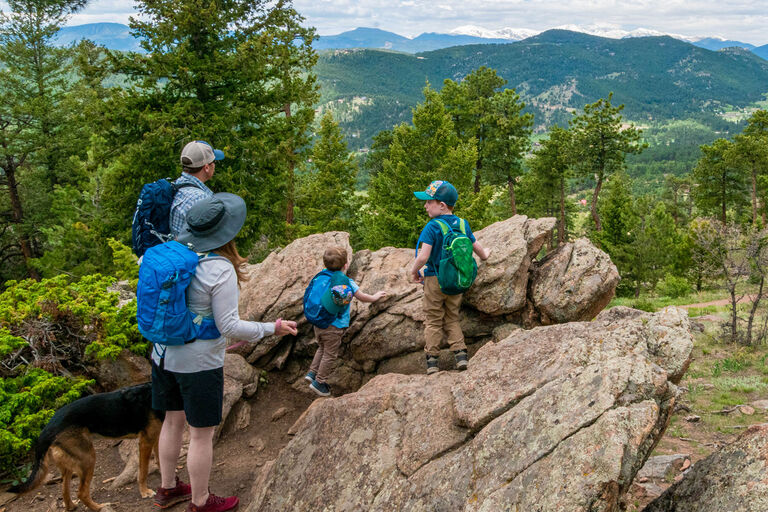 family hiking and kids playing on boulder