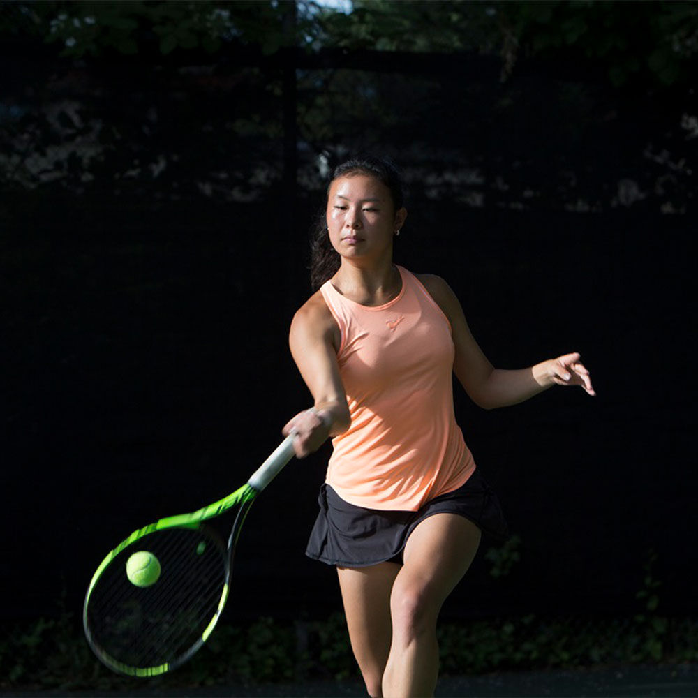 woman swinging a tennis racquet about to hit the ball