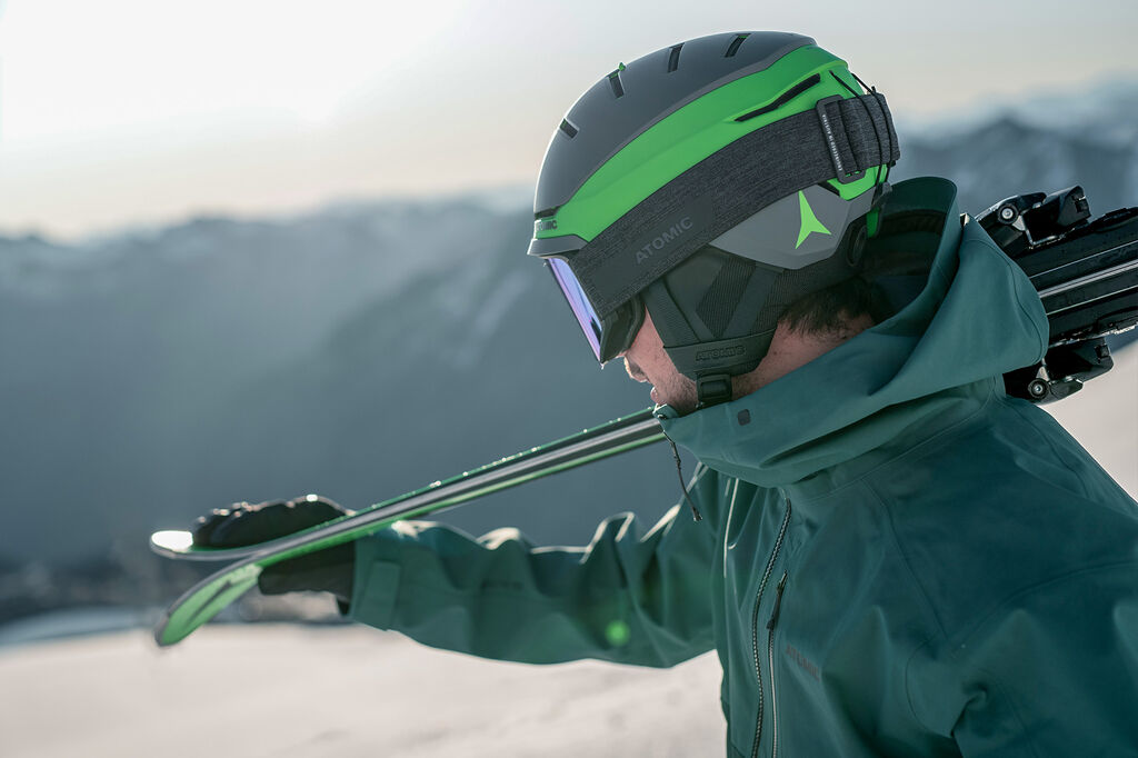 man holding skis wearing helmet