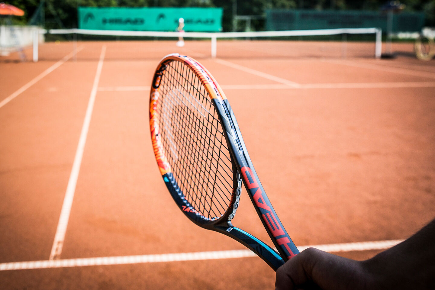 hand holding head tennis racquet and tennis court