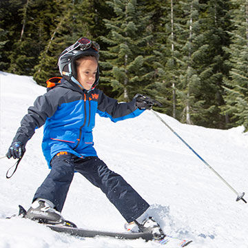 Kid girl skiing with ski poles and helmet