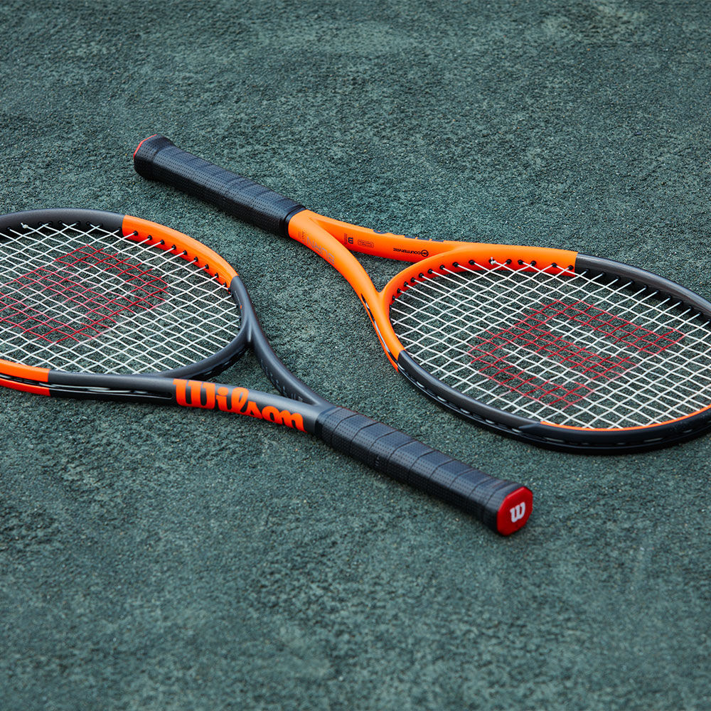 Two Wilson tennis racquets laying on court