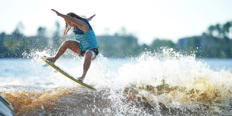 woman wakesurfing on lake with life jacket