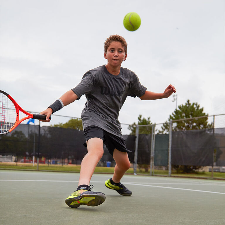 boy playing tennis concentrating on swing
