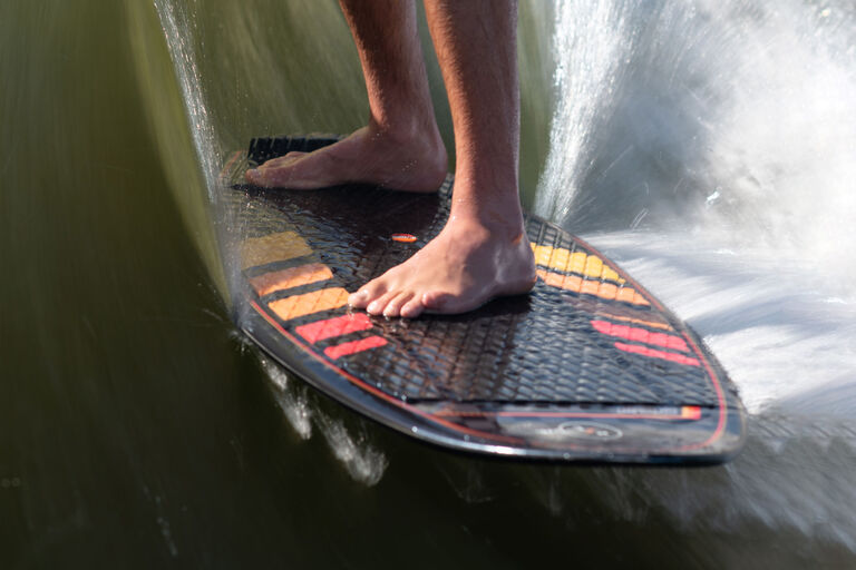 feet on wakesurf board on wave